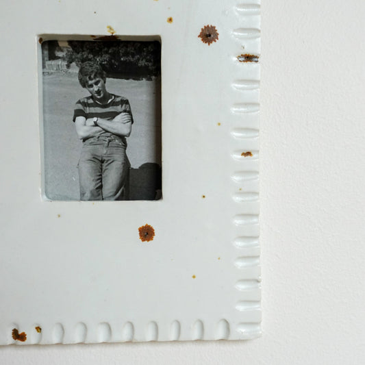 Vintage photo of a person in a striped shirt and jeans inside a white frame with a textured border.