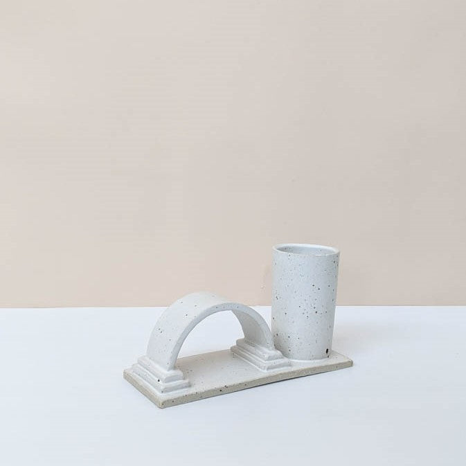 One arch budvase handmade by Oh Hey Grace in Melbourne photographed on a white and cream background. The budvase is finished in a speckled cream glaze.