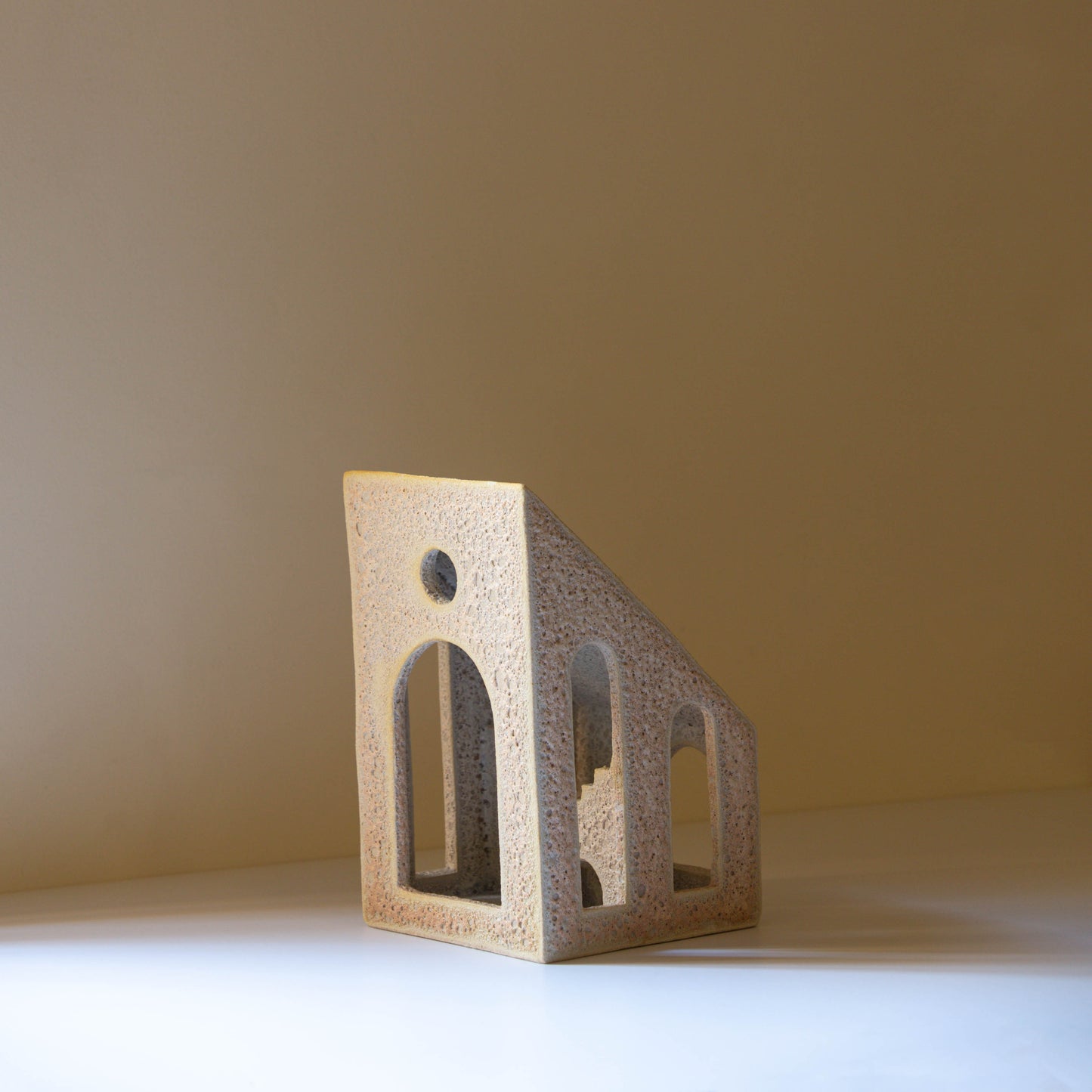 Handmade ceramic sculpture with textural glaze in a lavender, silver, and blush colour. The piece features cut out windows and archways as well as an internal staircase. 