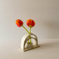 A handmade ceramic budvase on a white background. The budvase is finished in a white glaze and is is holding two orange tulips. 